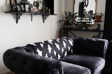 a chic Gothic living room with white walls, dark furniture, a shelf with cool objects on display and potted greenery