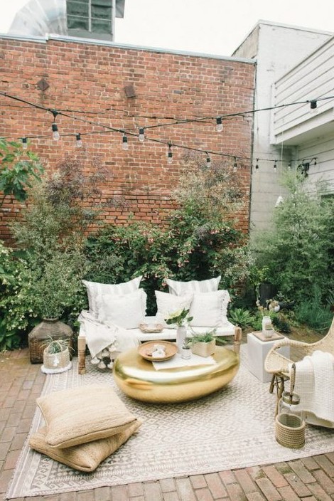 a chic eclectic neutral terrace with wooden and rattan furniture, stripes, gold touches and jute