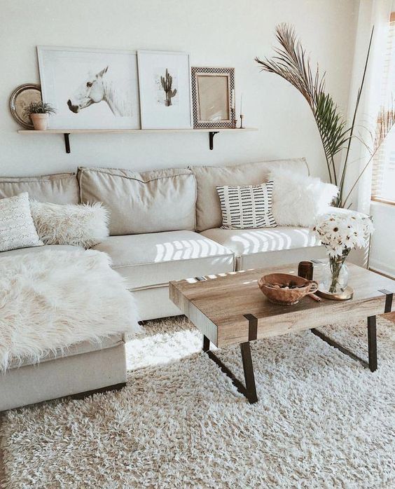 a chic neutral living room with a shelf gallery wall, a neutral sectional and mismatching pillows, a wooden slab coffee table and a statement plant