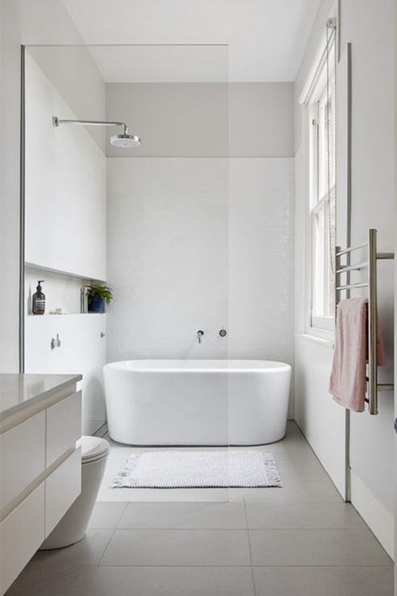 a contemporary bathroom with an oval bathtub, a sleek white vanity, a window and neutral textiles is a stylish space