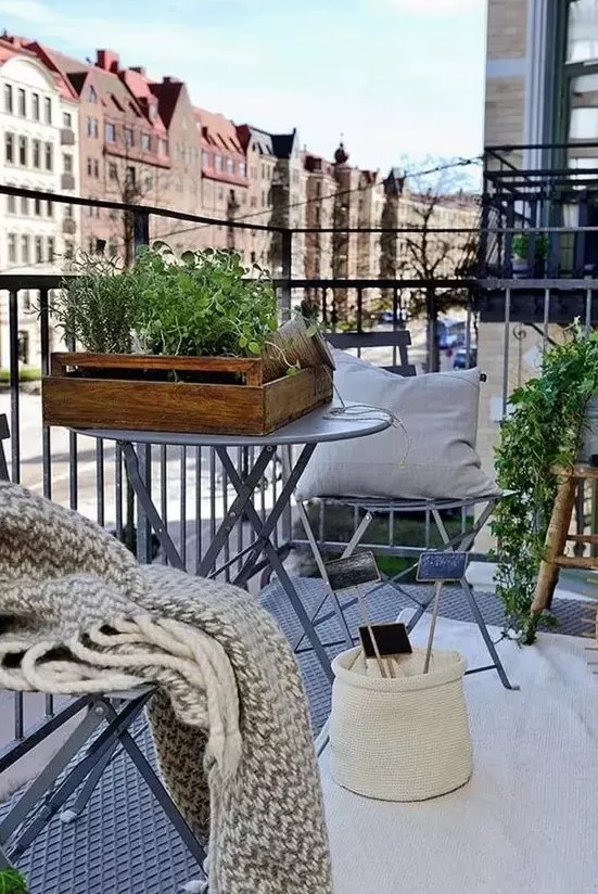 a cozy Scandi balcony, a rug, pillows, throws, potted plants and tiny coffee tables for winter