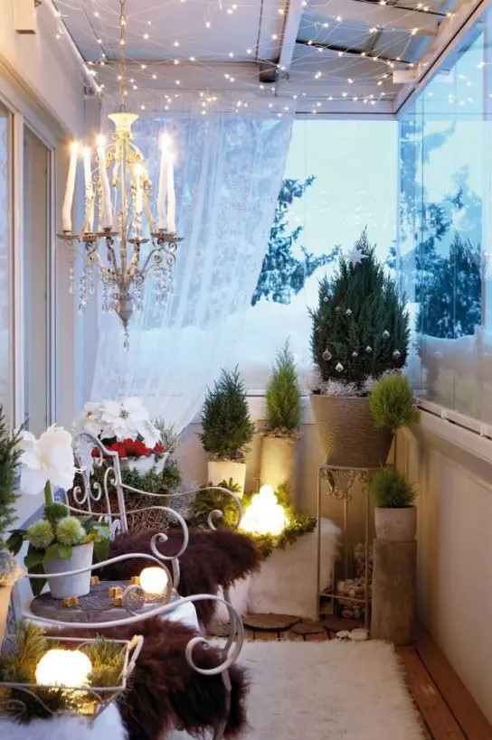 a cozy winter balcony done with mini Christmas trees, lots of faux fur, a crystal chandelier and lots of lights