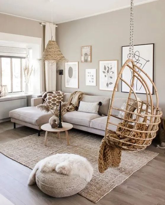 a greige living room with a neutral sectional, a gallery wall, a pendant egg chair, a woven lamp and some jute is a cozy space