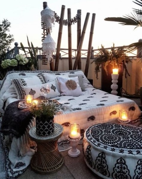 a gypsy-inspired monochromatic patio with candle lanterns, potted greenery and printed textiles all over