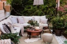 a lively neutral terrace with a corner sofa, a white pendant lamp, greenery and some boho accessories decorated for fall