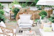 a lively summer terrace with rattan furniture, a comfy sofa, printed textiles, a low table and lots of greenery around