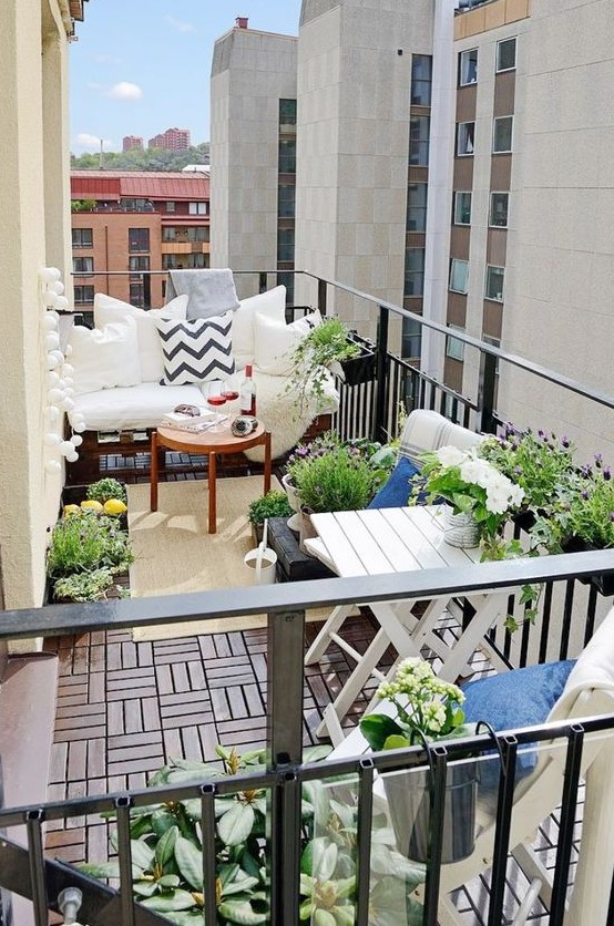 a lovely summer balcony with wooden furniture, potted plants and blooms and printed textiles is a cool space to be