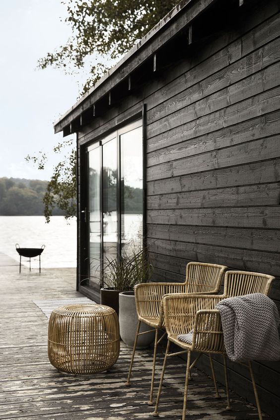 a minimalist back porch in Scandi style, with rattan chairs and a pouf, potted greenery is a lovely space to enjoy nature