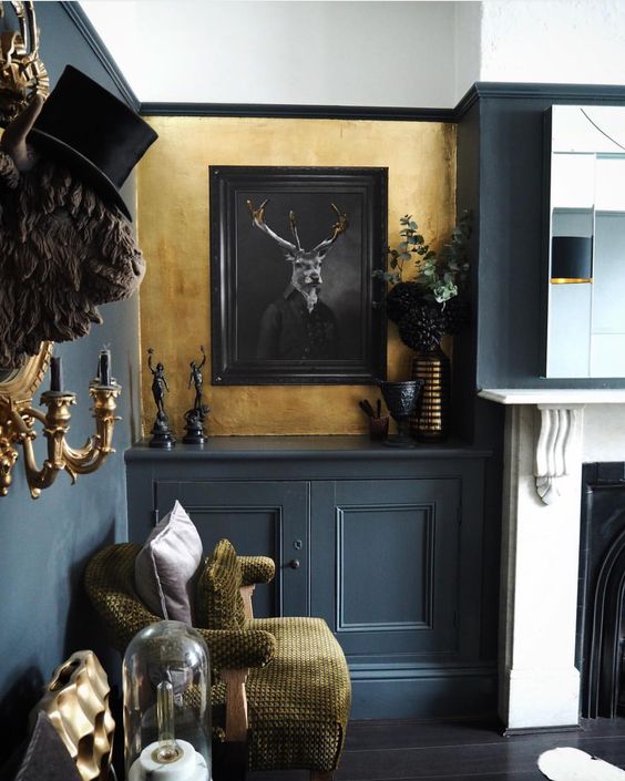 a modern and bright Gothic living room with grey and gold walls, a fireplace, grey paneling, gold touches and artworks (via raspberryflavouredwindows)