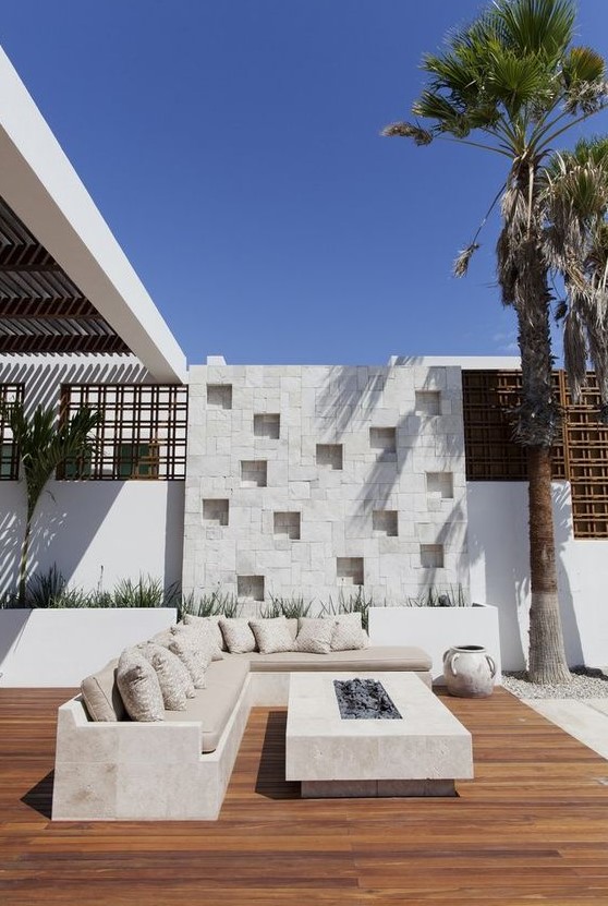 a modern neutral terrace with built in concrete furniture, a fire pit coffee table and potted greenery a modern neutral terrace with built-in concrete furniture, a fire pit coffee table and potted greenery