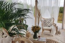 a neutral boho terrace with rattan chairs, black and white pillows, potted greenery and paper pendant lamps