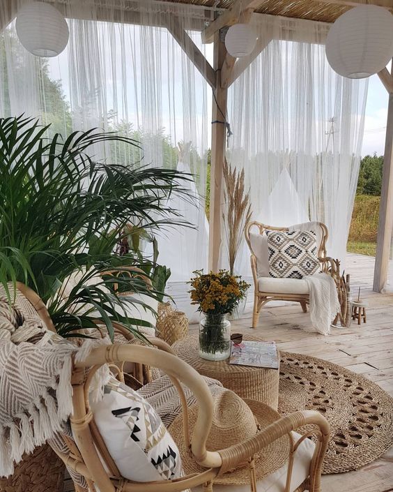 a neutral boho terrace with rattan chairs, black and white pillows, potted greenery and paper pendant lamps