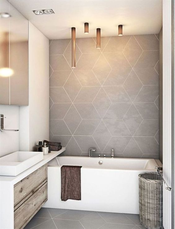 a neutral contemporary bathroom with grey tiles on the wall, a bathtub, a floating vanity and catchy tube lamps over the tub