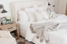 a neutral farmhouse bedroom with creamy furniture, artworks, neutral textiles and printed rugs and blankets