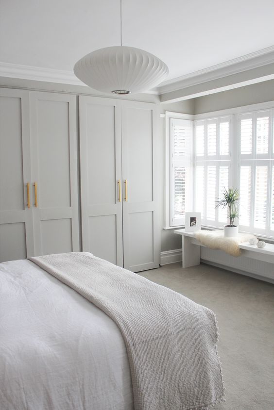 a neutral modern bedroom with ddove grey wardrobes, neutral furniture and a pendant lamp