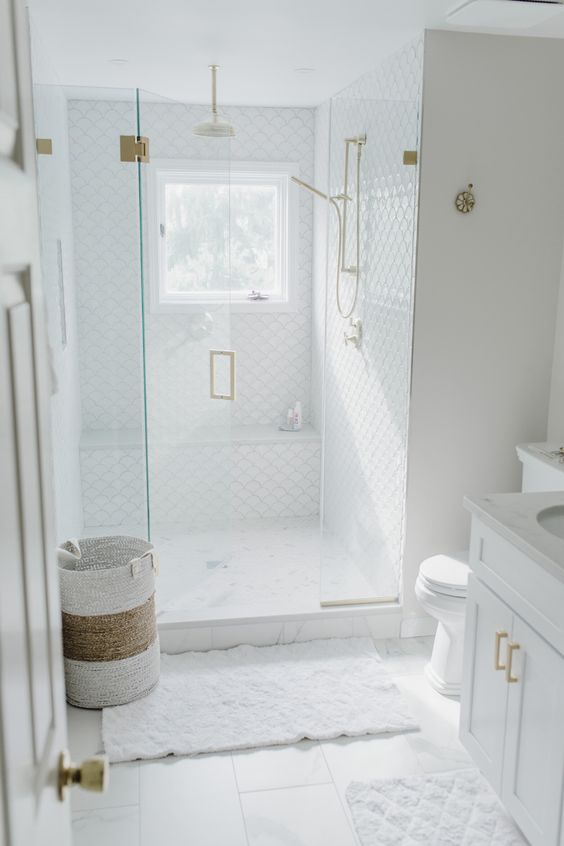 a neutral small bathroom clad with tiles, with a shower space, a vanity and gold touches is a lovely idea to rock