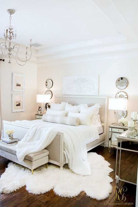 a neutral vintage bedroom with elegant furniture, decorative plates, a vintage chandelier and artworks
