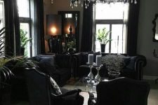 a refined Gothic space with elegant black furniture, a black chandelier and potted greenery