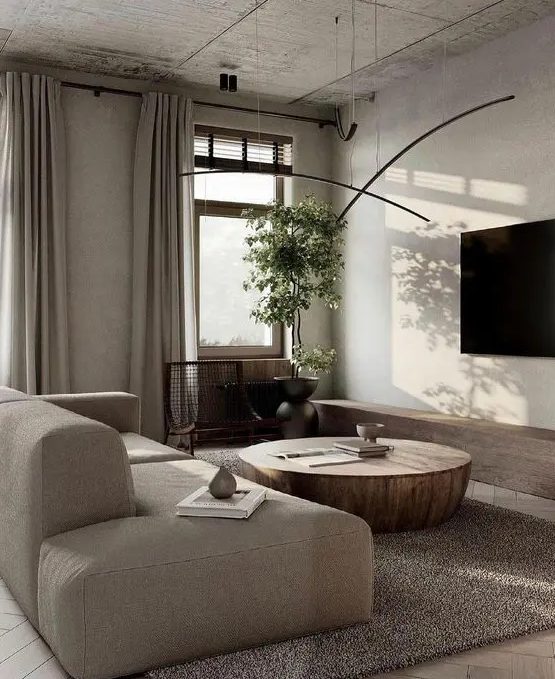 a refined contemporary greige living room with a neutral low sofa, a metal coffee table, pendant lamps and neutral curtains is chic
