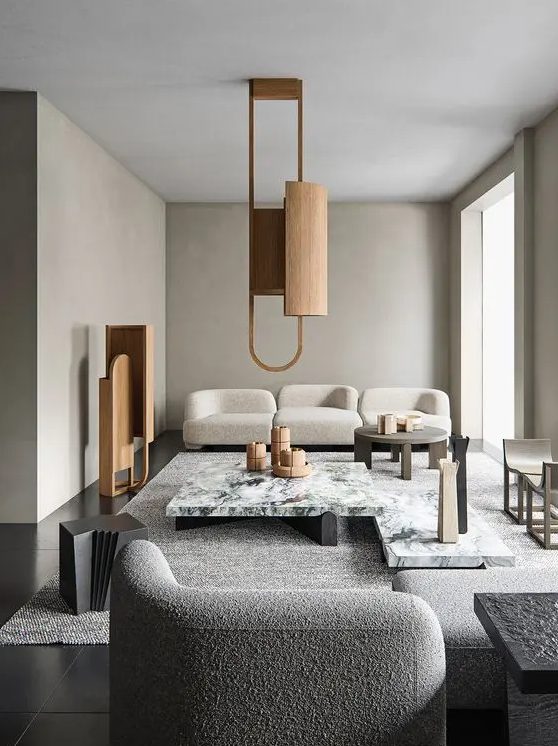 a refined greige living room with curved seating furniture, a white stone coffee table, a wooden pendant lamp and a matching decoration is chic