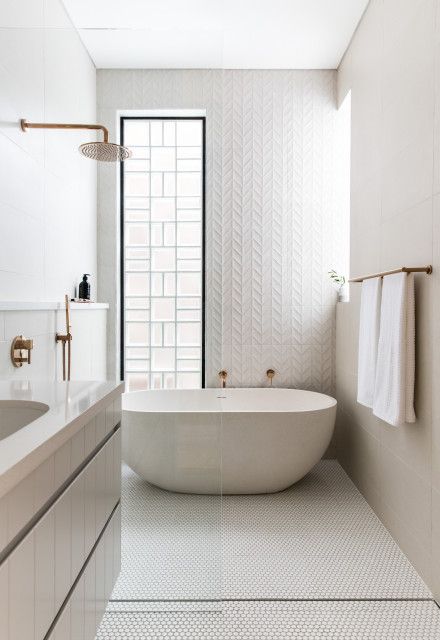 a refined modern white bathroom with a long and narrow window, an oval tub, various tules and a floating vanity with a sink