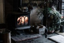 a rustic Gothic space with a vintage hearth, a firepit, potted plants, and black floors for a witch-like feel