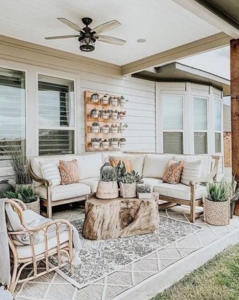 a rustic meets boho neutral terrace with rattan furniture, a tree stump, a vertical garden and layered rugs