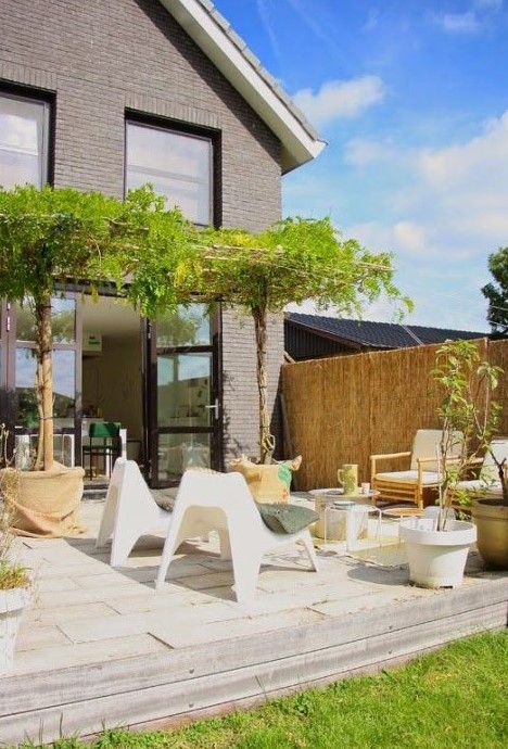 a simple neutral terrace with curved and simple wooden chairs, some colorful touches and potted trees