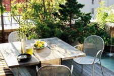 a small and cozy terrace with an upholstered bench, a wooden table, metal chairs and a mini garden in pots