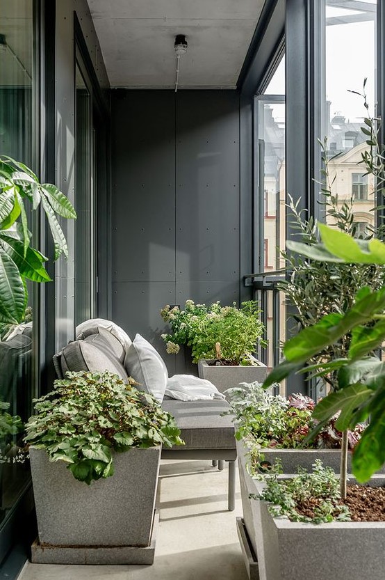 a small and laconic balcony with potted plants, a small grey loveseat and cool views is a lovely space to spend some time and relax