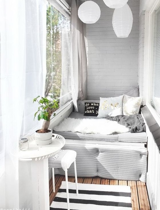 a small balcony with a daybed, a tiny table and stool, paper lanterns and sheer curtains is very welcoming
