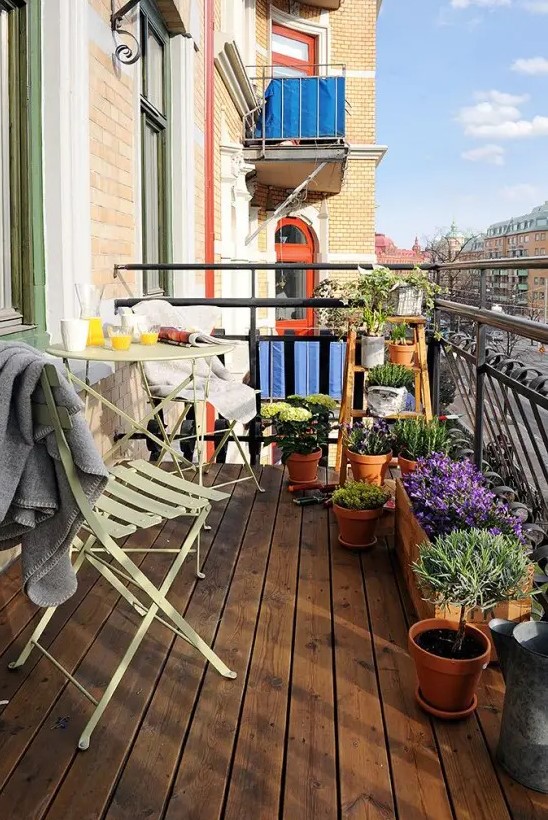 a small balcony with folding metal furniture and potted geenery and blooms is a simple and cozy space to enjoy fresh air