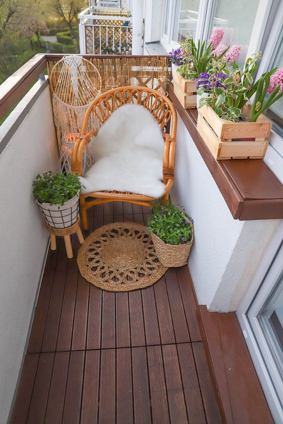 a small boho balcony with a rattan chair, potted greenery and plants, macrame, a jute rug is a cool space