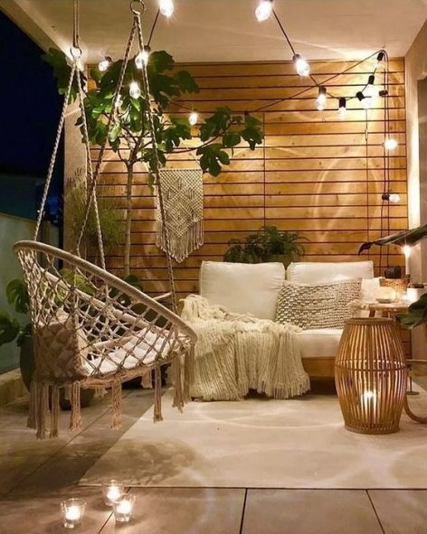 a small contemporary meets boho terrace with lights, macrame, candles and greenery plus enough light