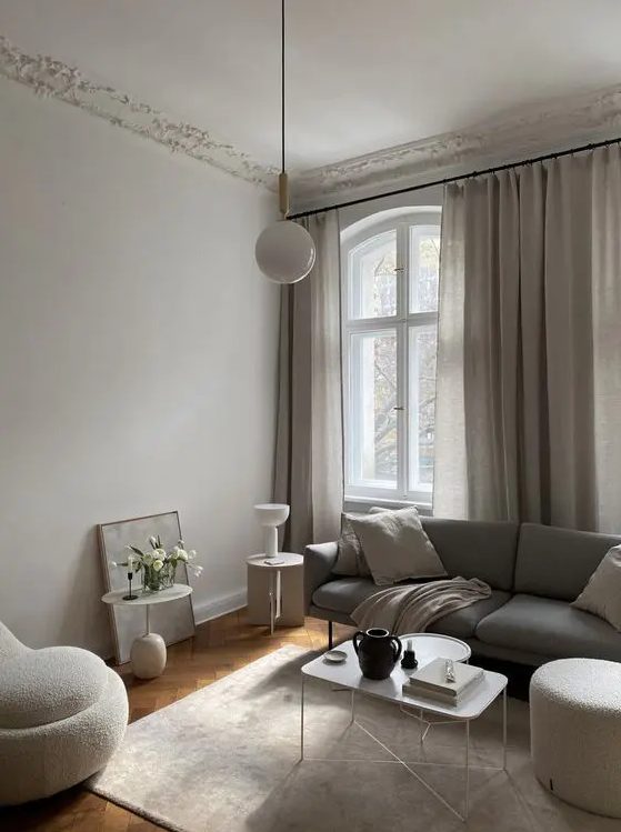 a stylish greige liivng room with a grey sofa, neutral seating furniture, a lightweight coffee table, some pendant and usual lamps