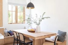 a stylish modern dining space with a stained built-in bench, a stained table and black wooden and cane chairs plus printed pillows