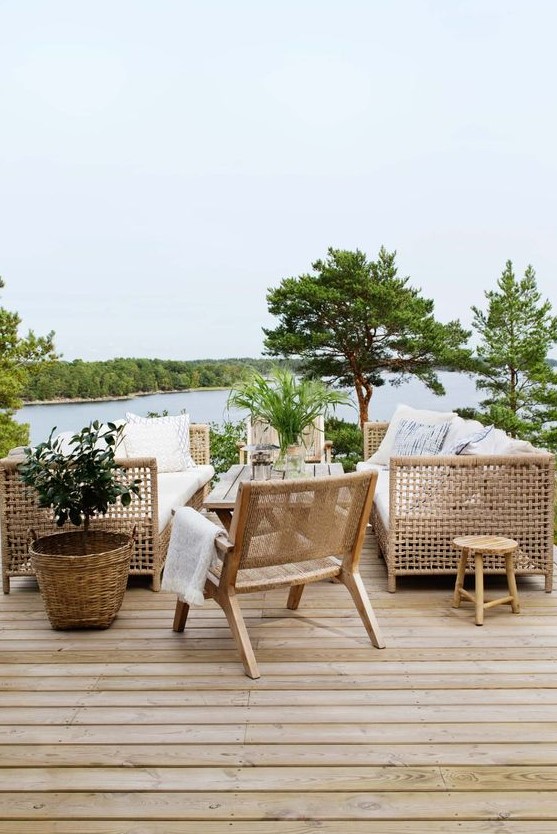 a summer terrace with a river view, wooden and rattan furniture, trees and greenery around and printed textiles