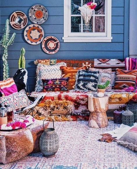 a super bright boho terrace with printed and colorful textiles, decorative baskets, lanterns and potted cacti for a desert feel