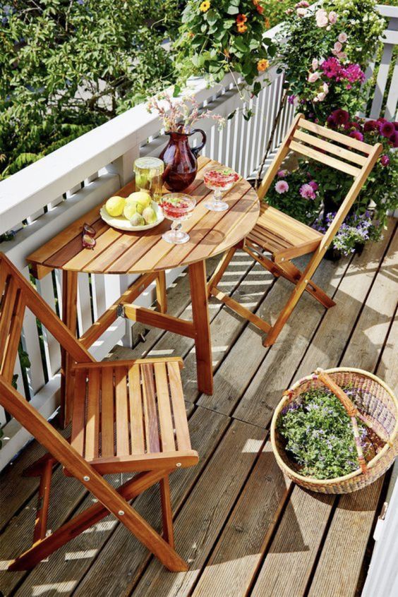 a tiny and lovely balcony with folding furniture, potted plants and blooms and a basket is a gorgeous space