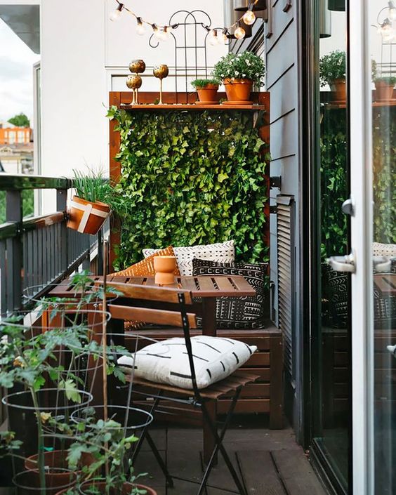 a tiny balcony with a living wall and potted plants, IKEA outdoor furniture and some printed pillows and lights