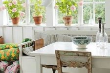 a vintage Nordic sunroom with a checked green and white floor, vintage white and stained furniture, colorful blankets and potted blooms