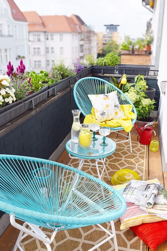a vivacious summer balcony with blue furniture, colorful pillows and textiles and some poted blooms is welcoming