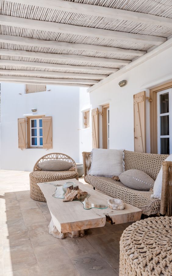 a welcoming neutral boho meets modern terrace with a low coffee table, wicker furniture with neutral pillows and cushions