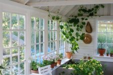 a white Scandi sunroom with a white dining set, lots of greenery and blooms is a cozy space to have a drink