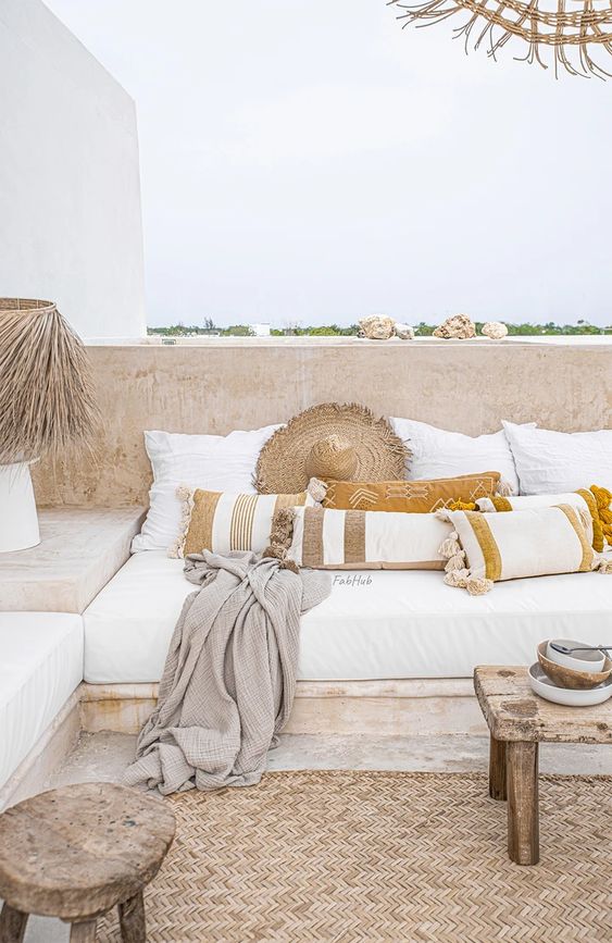 aneutral boho terrace with a built-in bench with neutral cushions and pillows, striped pillows, a jute rug and a low coffee table