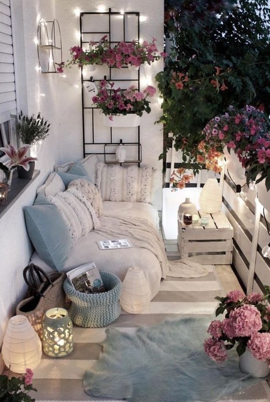 light blue pillows and a basket, potted pink flowers and some lights and lanterns will make your balcony tender and spring-like