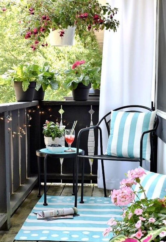 light blue printed pillows and a rug and potted pink flowers turn this balcony in a light inviting space