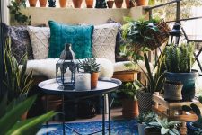 a Morocco-inspired balcony with a bold blue rug, a loveseat with boho pillows, a side table, potted plants and cacti, Moroccan lanterns