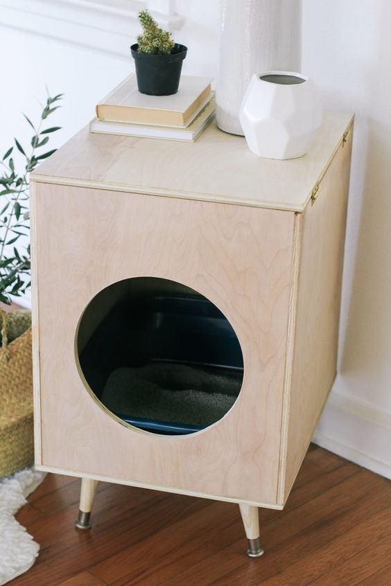 a Scandinavian cat litter box cover of plywood, with a round entrance and on legs can double as a side table