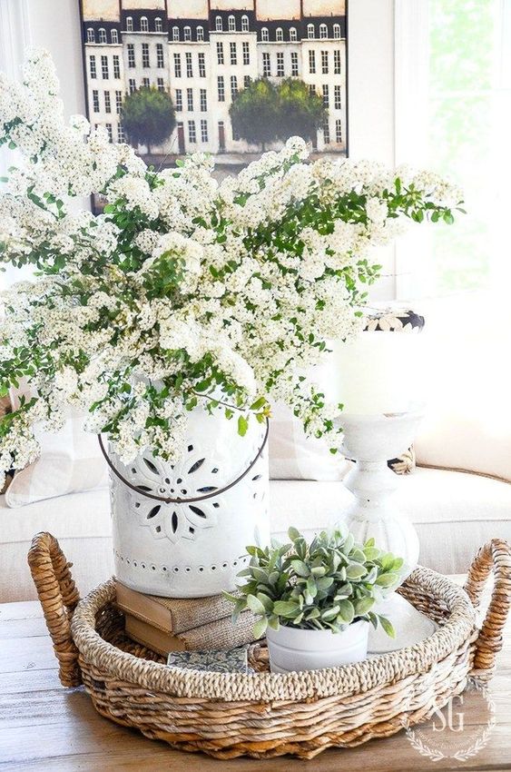 a basket tray with potted greenery, a vase with white blooming branches is a lush spring decoration